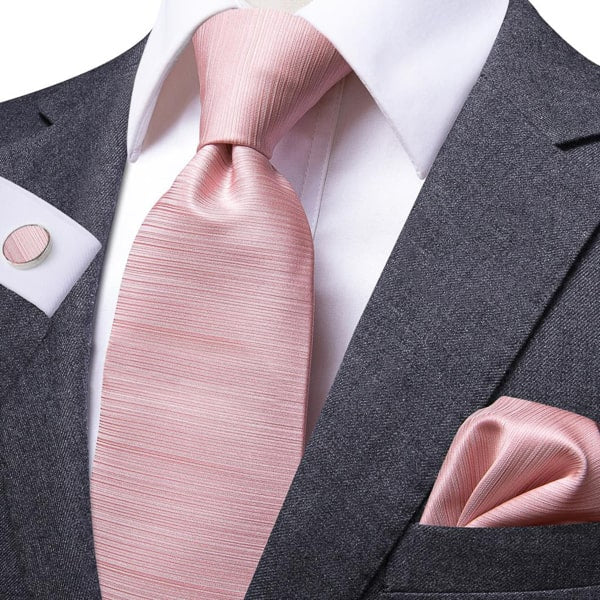 Baby pink rose gold silk tie, pocket square, and cufflinks on a suit