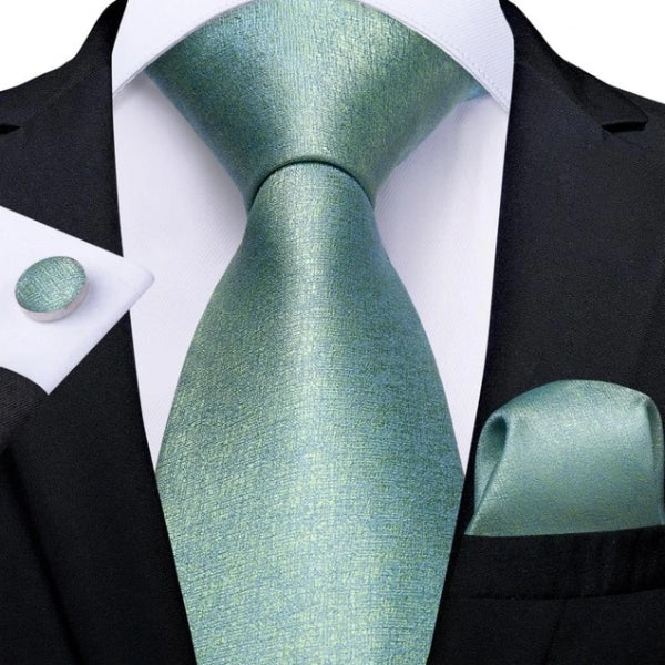 Mint green & teal static noise silk tie, pocket square, and cufflinks set on a suit