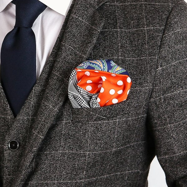 Navy blue and orange multi-pattern pocket square in suit pocket