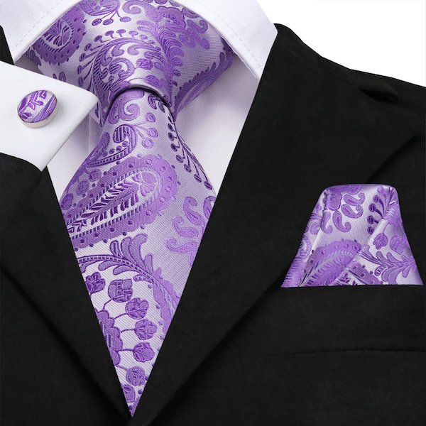 Man wearing a lavender purple paisley flower silk tie with a matching pocket square and cufflinks