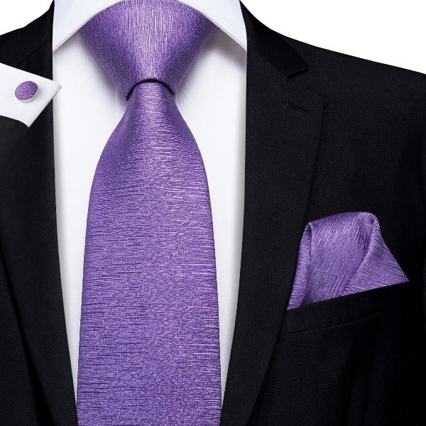 Man wearing a violet silk tie set with a matching pocket square and cufflinks