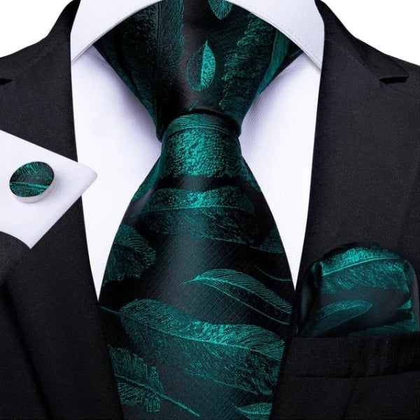 Black & green silk feather tie, pocket square, and cufflinks on a suit